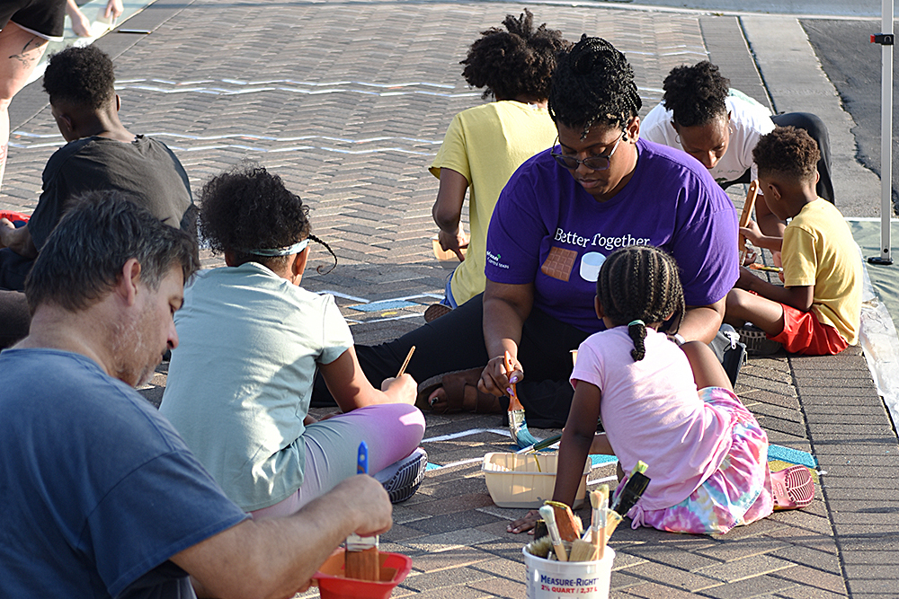 Volunteers painting sidewalk.
